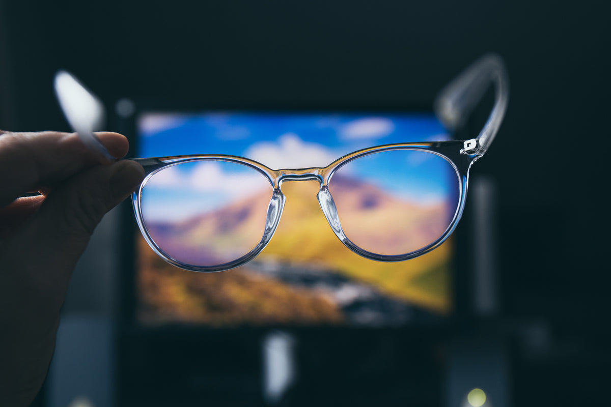 Glasses held in front of a blurred scenic background