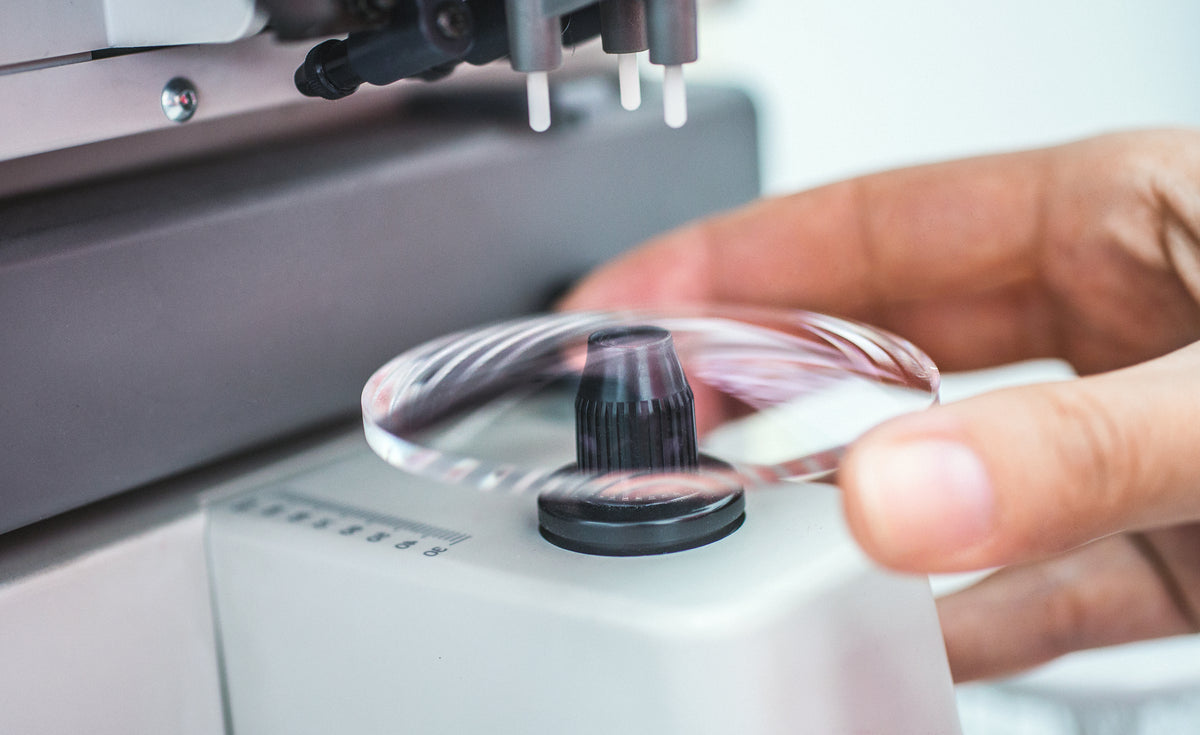 Person adjusting a dial on a piece of medical equipment for lenses